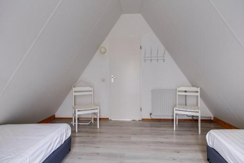 two beds and two chairs in a attic room at Graspieper I Vrijstaand Huisje met Brede Tuin in Zwiggelte