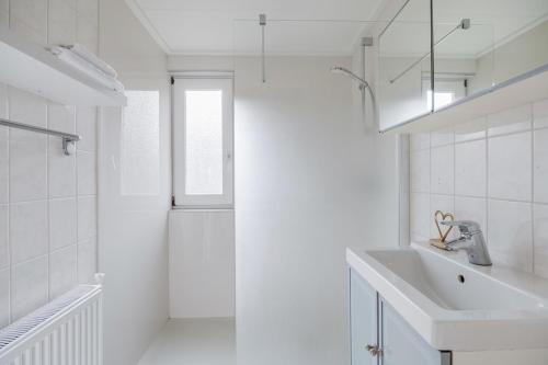 a white bathroom with a sink and a shower at Graspieper I Vrijstaand Huisje met Brede Tuin in Zwiggelte