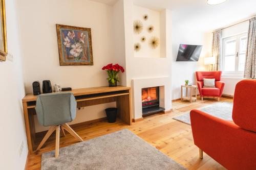 a living room with a desk and a fireplace at Hubertus Boutiquehotel Filzmoos in Filzmoos