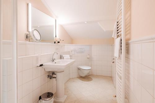 a white bathroom with a sink and a toilet at Hubertus Boutiquehotel Filzmoos in Filzmoos