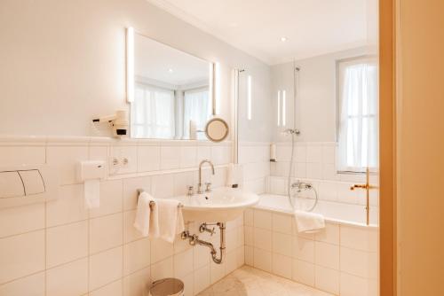 a bathroom with a sink and a tub and a mirror at Hubertus Boutiquehotel Filzmoos in Filzmoos