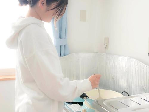 a woman standing in a kitchen preparing food at Guest House Isehutami - Vacation STAY 89326v in Ise