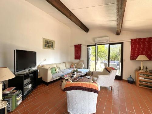 un salon avec des canapés et une télévision à écran plat dans l'établissement Mazet Gaspard climatisé pour 7 personnes sur le Domaine de Valcros à la Londe Les-Maures, à La Londe-les-Maures