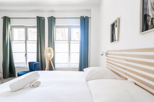 - une chambre avec 2 lits blancs et des rideaux bleus dans l'établissement Le Hardi, à Dijon