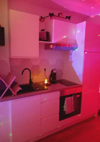 a pink kitchen with a sink and a stove at Heaven Loft in Yvetot