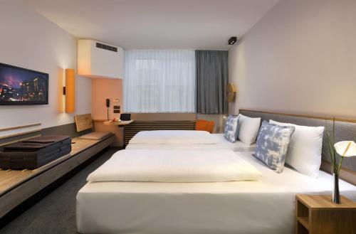 a hotel room with two beds and a tv at Flemings Express Hotel Frankfurt in Frankfurt