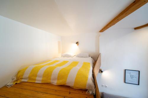 - une chambre avec un lit à rayures jaunes et blanches dans l'établissement Appartement tout equipé 4 couchages à 600m de la Plage des Catalans, à Marseille
