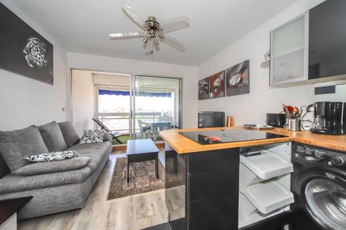 a kitchen and living room with a couch and a table at Le Bella Vista Vue Port Carnon Proche Plage in Mauguio