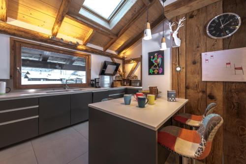 - une cuisine avec une table, un évier et une horloge dans l'établissement Chalet Les Rots Home, à Samoëns