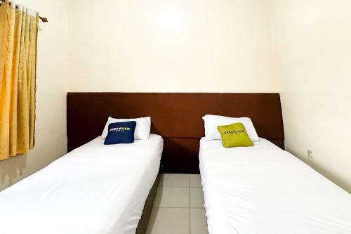 two beds sitting next to each other in a room at Urbanview Hotel Sabitha Kalijati Subang in Dawuhan