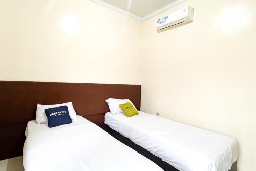 two beds sitting next to each other in a room at Urbanview Hotel Sabitha Kalijati Subang in Dawuhan