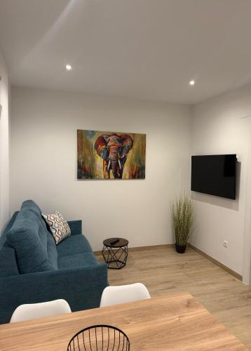 a living room with a blue couch and a tv at Apartamento Mar in Benajarafe