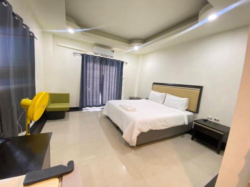 a bedroom with a white bed and a yellow chair at Buddy hotel in Pattaya