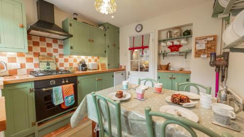 a kitchen with green cabinets and a table with food on it at Wheelhouse in Southwold