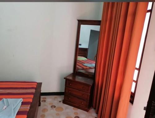 a bedroom with a dresser and a mirror and a bed at Iwaree Guest house in Dambulla