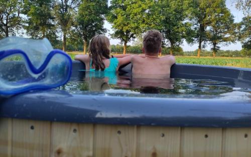 a boy and a girl sitting in a hot tub at Tiny house met privé hottub in Vledder
