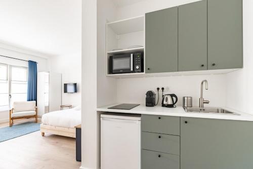 une cuisine blanche avec un évier et un micro-ondes dans l'établissement Le Valeureux - Cosy en hypercentre, à Dijon