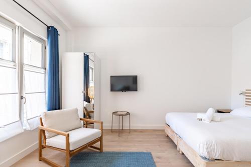 - une chambre avec un lit, une chaise et une télévision dans l'établissement Le Valeureux - Cosy en hypercentre, à Dijon