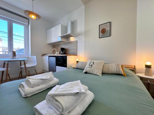 - une chambre avec un grand lit vert et des serviettes dans l'établissement Les studios de la gare - Centre Le Mans - Calme, au Mans