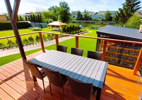 a wooden deck with a blue table and chairs at 4jeziora - prywatny dostęp do rzeki, pomost, ogrodem, wiata grillowa, rowerek wodny, kajaki w cenie, parking, psiaki dozwolone in Iława