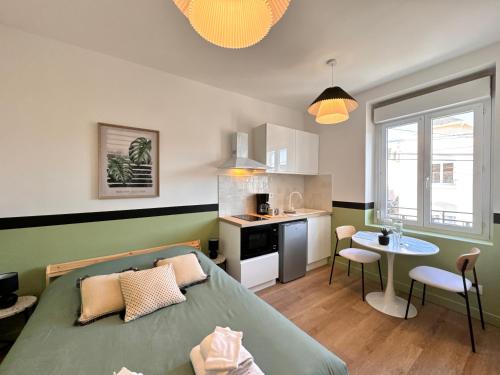une chambre avec un lit et une table et une cuisine dans l'établissement Les studios de la gare - Centre Le Mans - Calme, au Mans