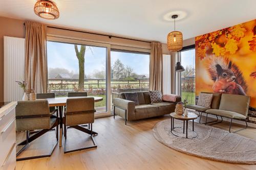 a living room with a table and chairs and a large window at Lodge de Eekhoorn in Putten