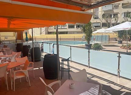 restauracja ze stołami i krzesłami oraz basen w obiekcie Paraty de SteraM flats Torremolinos w mieście Torremolinos