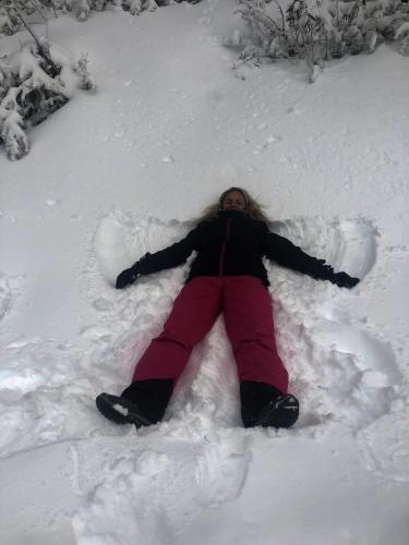 a woman is laying in the snow at 5min Walk to Lift 3BR Luxe Chalet with Views & Fire in Mount Buller