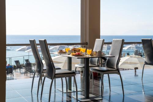 a table with a plate of food on a balcony with the ocean at La Luna Hotel in Troulos