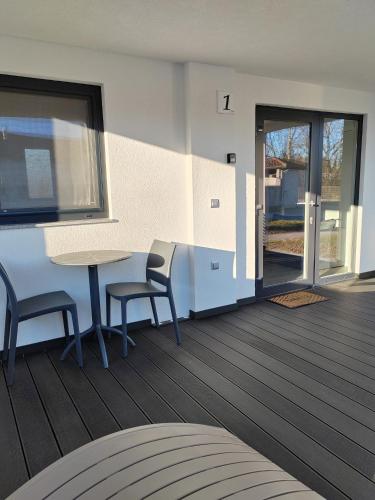a patio with a table and two chairs and a door at Prenočišča Kogoj in Miren