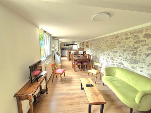 a living room with a green couch and a table at Le Pont Bas bord de rivière proche Puy du Fou in Mortagne-sur-Sèvre