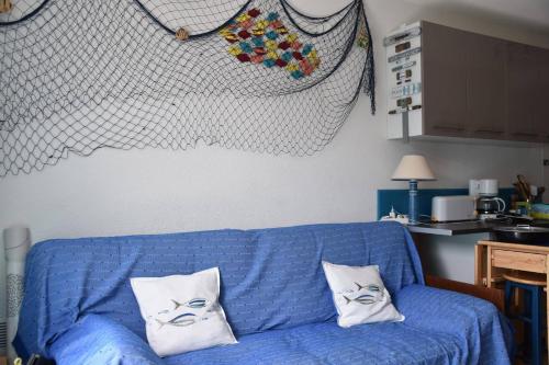 - un canapé bleu dans une cuisine avec 2 oreillers dans l'établissement Maison 3 pièces - Gruissan GA070-040, à Gruissan