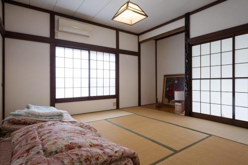 a bedroom with a bed and large windows at Yanesen Traditional Nagaya house in Tokyo