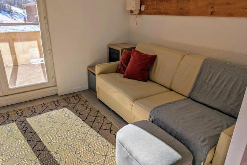 un salon avec un canapé et une fenêtre dans l'établissement Cozy T1 with balcony on the snow front, à Les Deux Alpes
