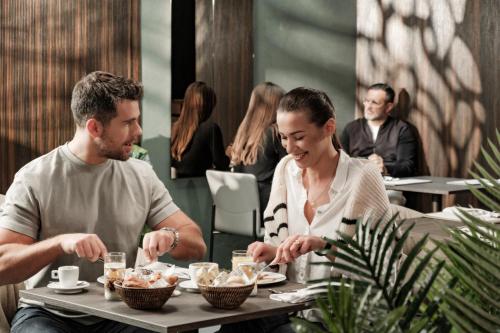 a man and woman sitting at a table eating food at Fitch Hotel in St Julian's