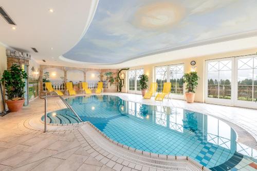 a swimming pool in a building with yellow chairs at Reisslerhof Hotel & Apartments - by myNests in Gröbming