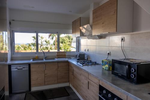 a kitchen with a stove and a microwave at La Villa Des Pêcheurs in Filaos