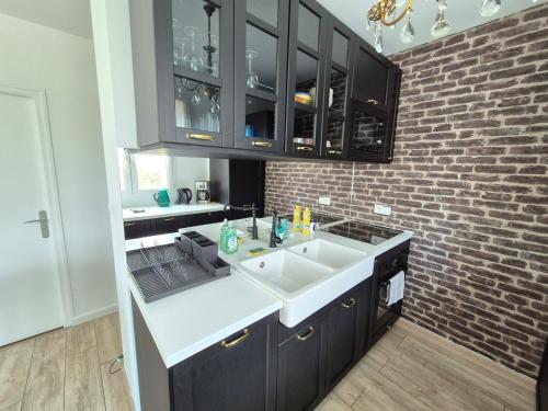 - une cuisine avec un évier et un mur en briques dans l'établissement La Terrasse de Rochard Maison 6p proche Puy du Fou, à Mortagne-sur-Sèvre