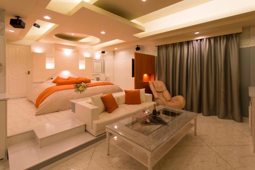 a bedroom with a bed and a couch and a table at ホテルベノアリゾート in Kobe