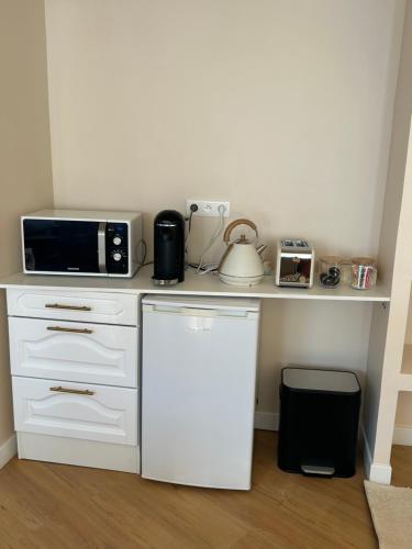 a white kitchen with a microwave and a refrigerator at Le Chalet - maison avec jardin et parking in Lourdes