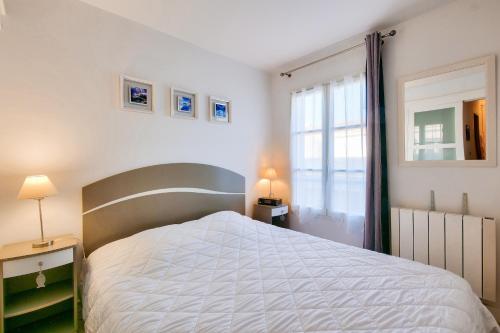 a bedroom with a white bed and a window at Escale à deux au coeur de l'île de Ré - La Rétaise in Saint-Martin-de-Ré