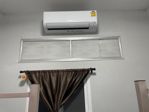 a room with a television and a window with a curtain at Zou Hostel in Phangnga