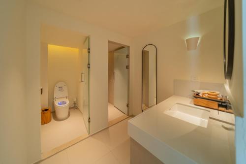 a white bathroom with a sink and a toilet at 礼橖LoveTime·美学海景民宿（较场尾大鹏所城店） in Shenzhen