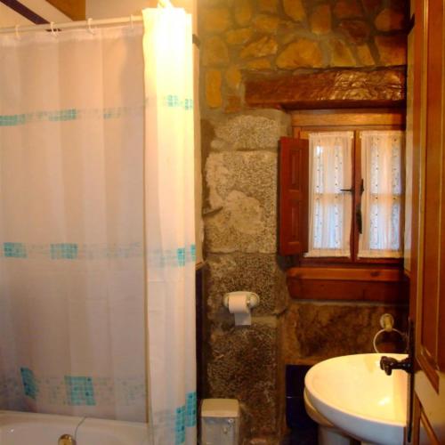 a bathroom with a white shower curtain and a sink at Las Casucas de Ason in Arredondo