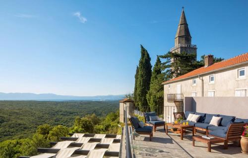 a patio with chairs and a building with a tower at Beautiful Villa Palazzo Adriana Krk in Dobrinj