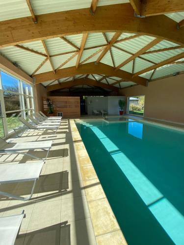 an indoor swimming pool with a wooden ceiling at Résidence de Nodeven in Guissény