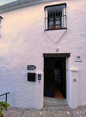 a white building with a black door and a window at Casa El Barbero 1810 in Benaocaz