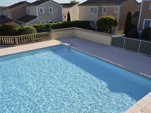 - une grande piscine bleue dans une cour avec des maisons dans l'établissement Bastide cozy Au petit olivier d 'Uzes, à Uzès