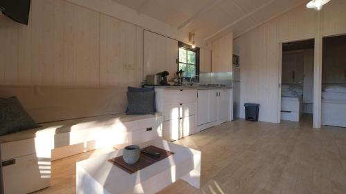 a living room with a couch and a kitchen at Les Cabanes de Lara in Ménesplet