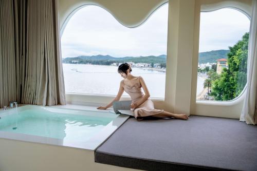 a woman sitting on the floor in a window with a laptop at 礼橖LoveTime·美学海景民宿（较场尾大鹏所城店） in Shenzhen